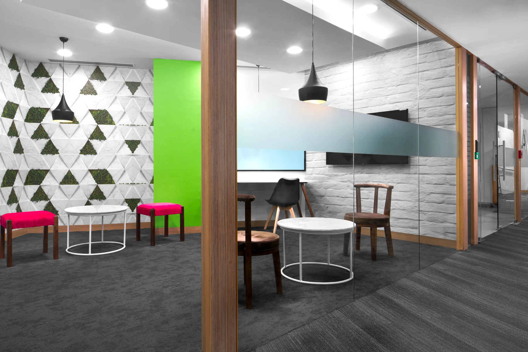 Glass-partitioned meeting area beside a patterned wall and brightly coloured seating.