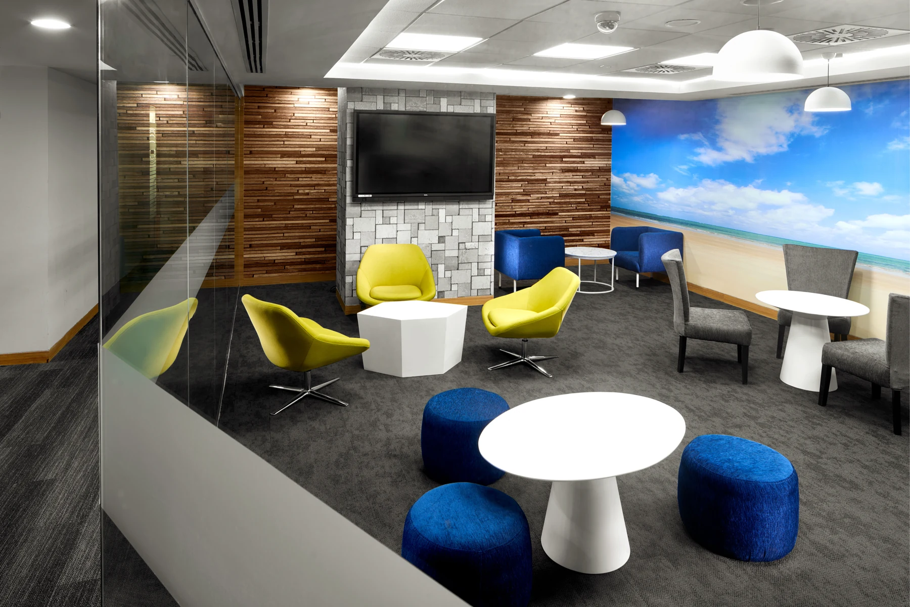 Breakout area with lime-toned chairs, blue stools and small round tables.