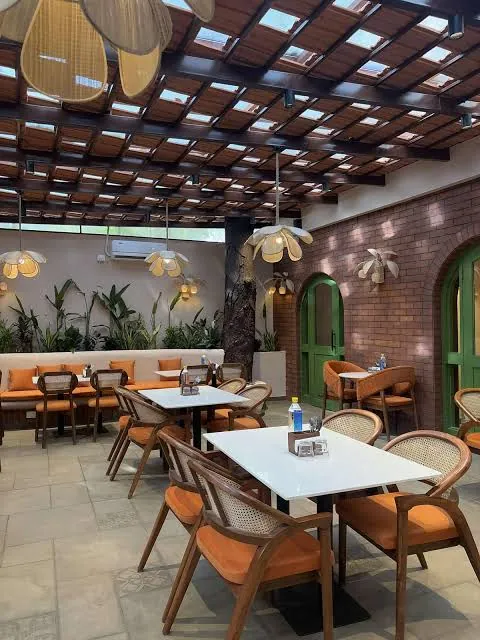 Beanery Café dining area with orange cushions, green arches and a canopy.