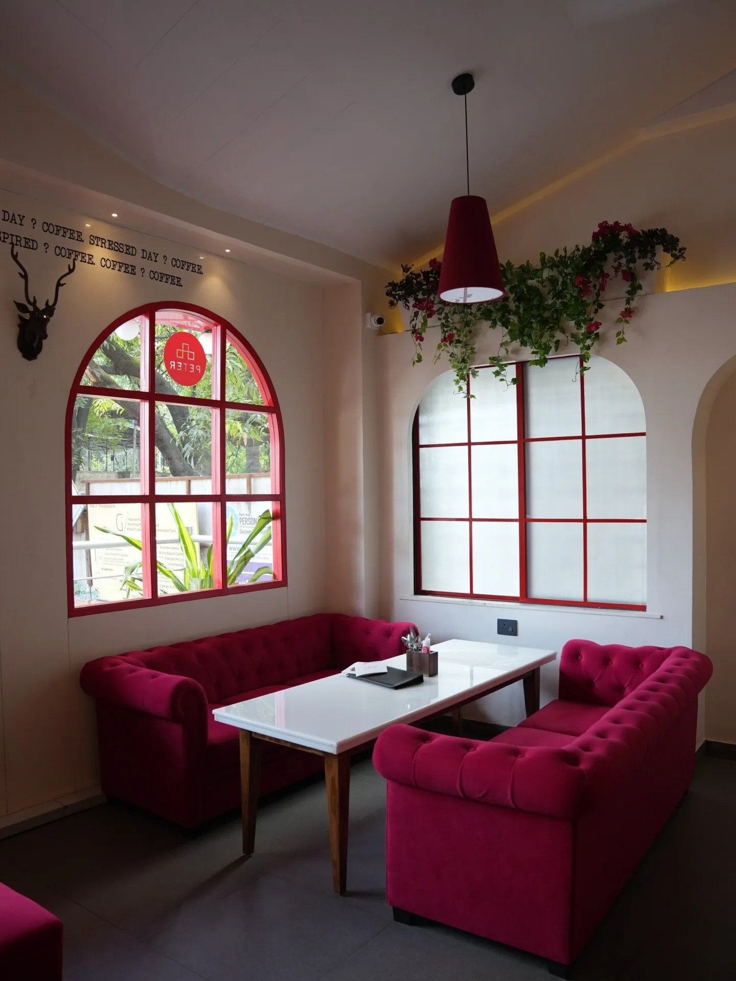 Arched red-framed sofa seating bay inside Café Peter Erandwane Pune — hospitality interior by prāngaṇa.