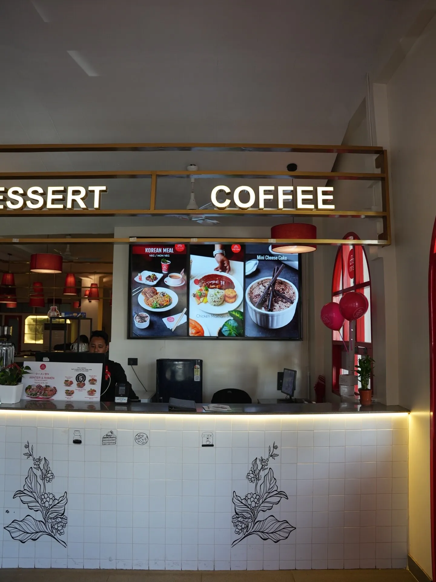 Front counter and display area at Café Peter Erandwane Pune — red accents and warm cafe interior by prāngaṇa.