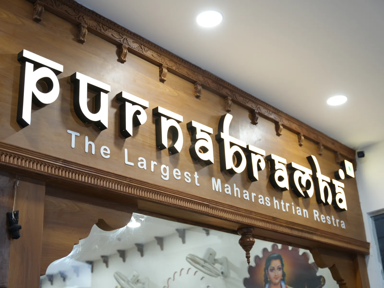 Illuminated Purnabramha restaurant sign below carved trim above the entrance.