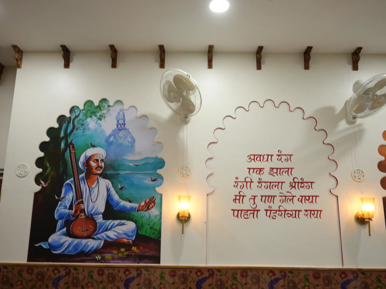 Artwork of a seated musician beside Marathi lettering and lamps at Purnabramha.