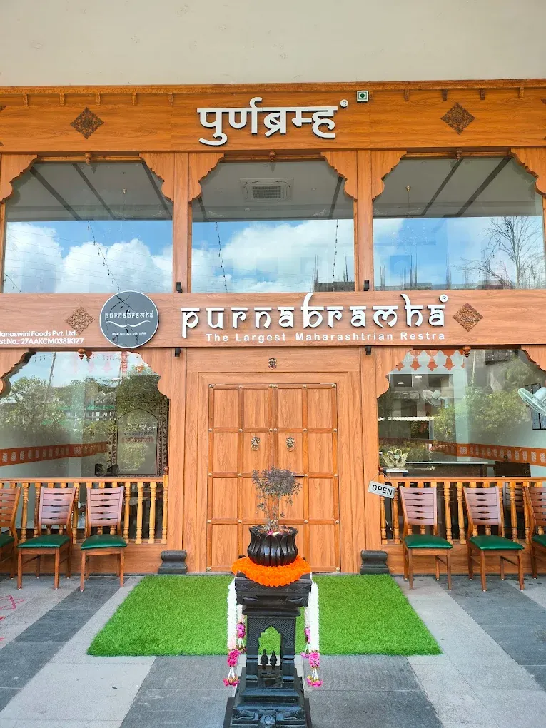 Purnabramha front entrance with wooden doors, signage and chairs.
