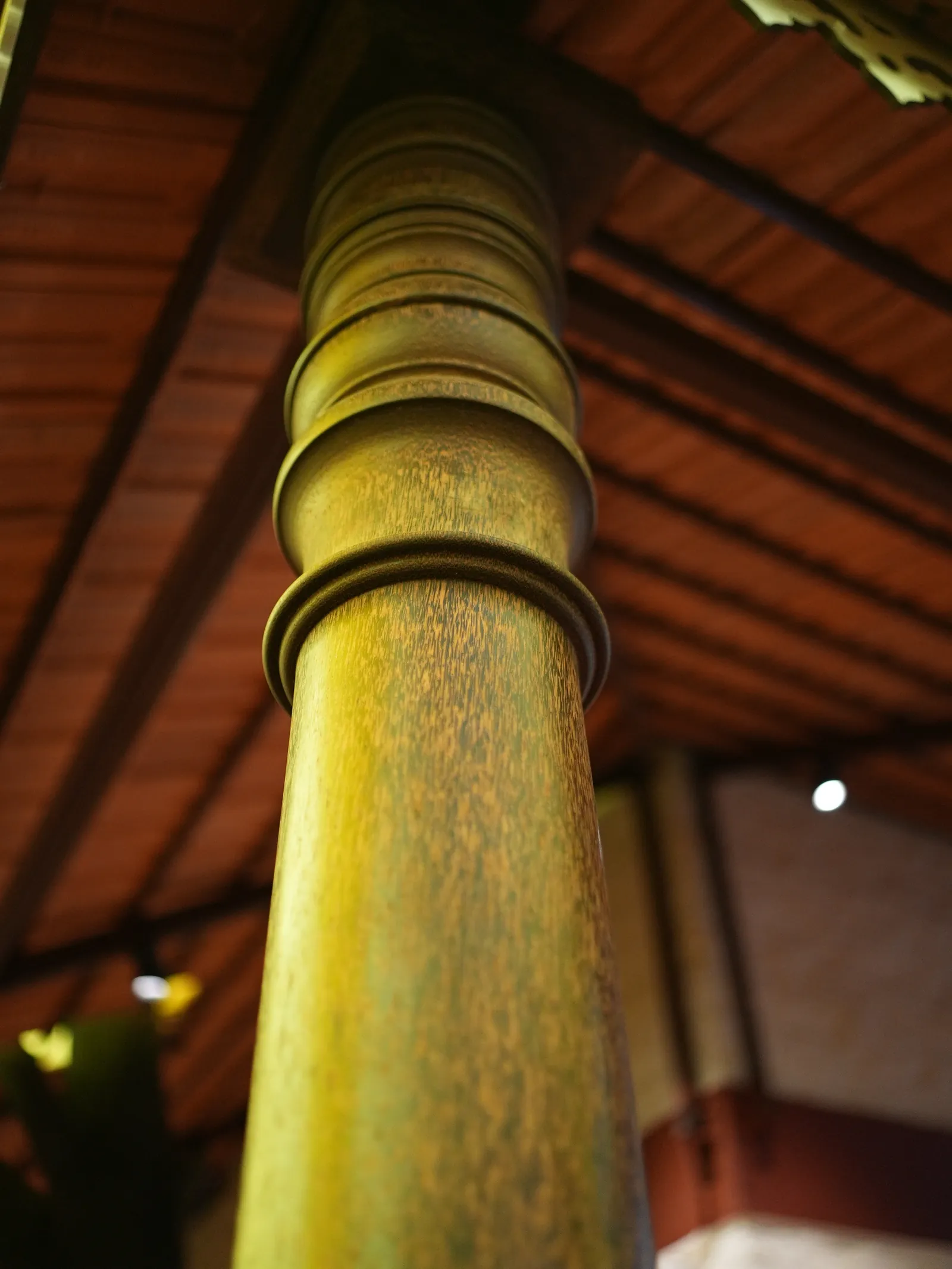 Green and gold-toned vertical detail beneath the roof at Secret Sambar.