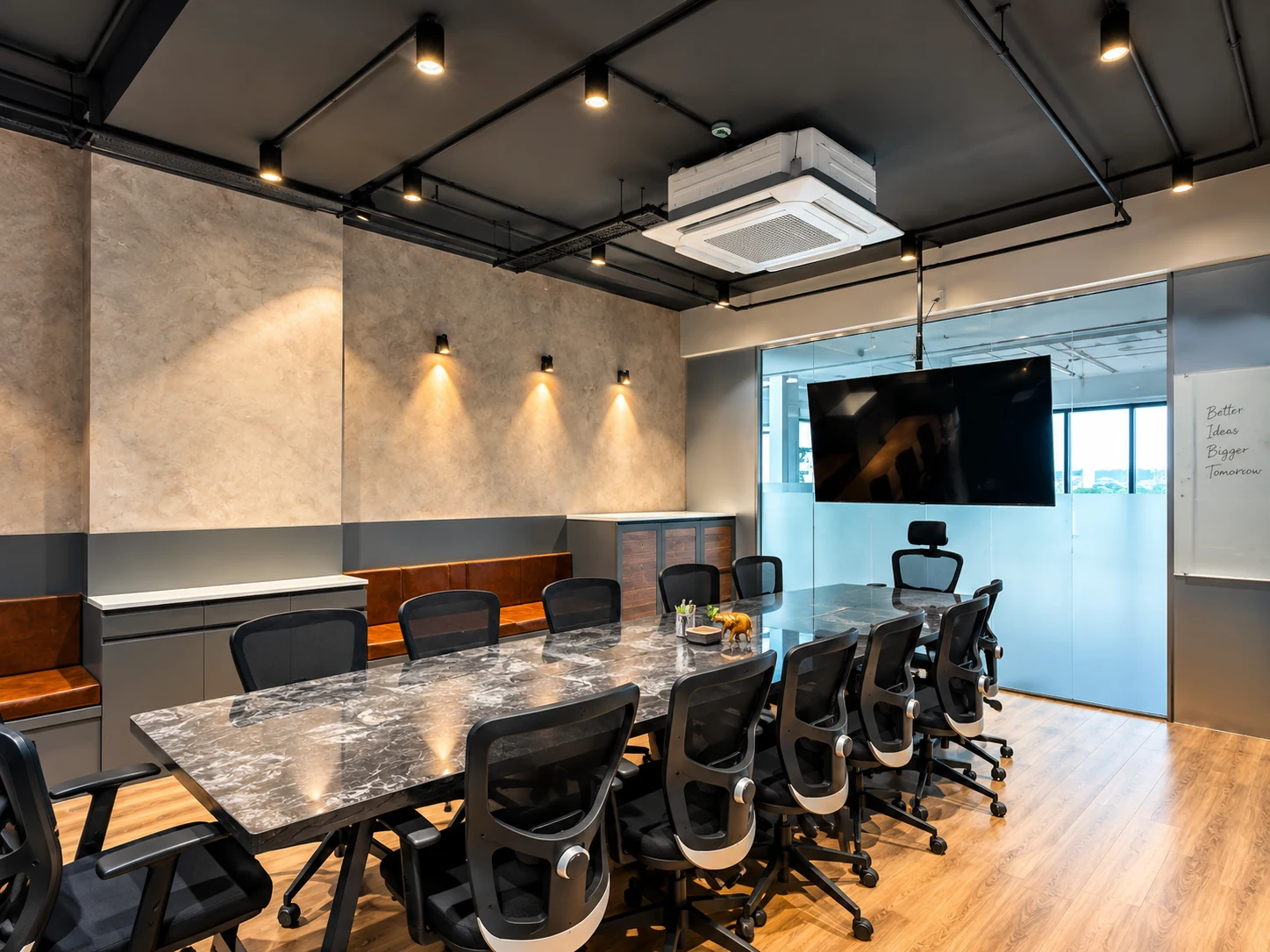 Meeting room with a long table, dark ceiling, grey wall finishes and glazed partition.