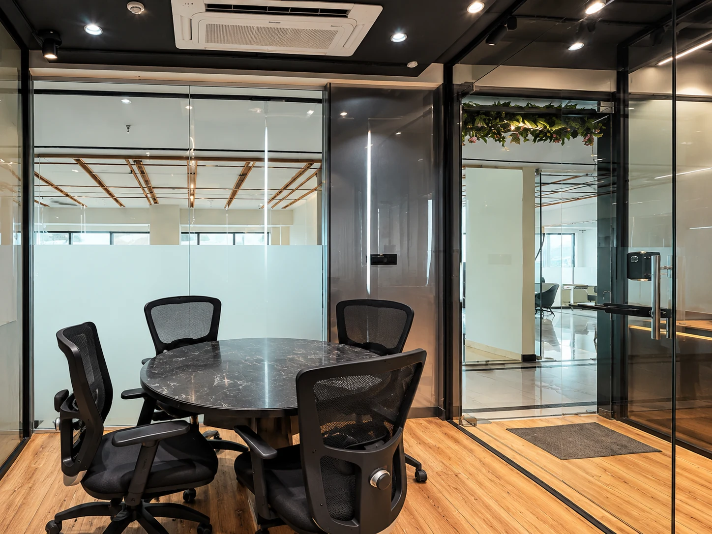 Round meeting table inside a black-framed glazed room.